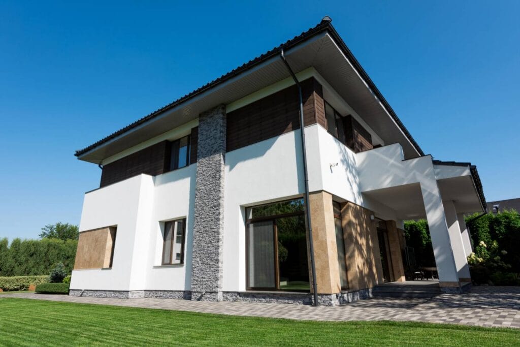 Modernes zweistöckiges Haus mit weißen Wänden, großen Fenstern und einem gepflegten grünen Rasen unter freiem Himmel - ideal für Immobilien in Deutschland mit solider Finanzplanung.