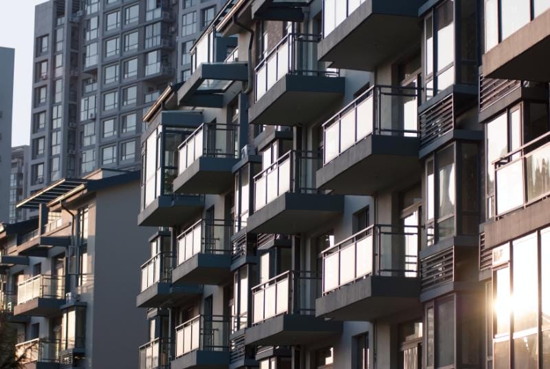 Moderne Mehrfamilienhäuser mit Glasbalkonen, die das Sonnenlicht in einer städtischen Umgebung reflektieren, ideal für Immobilieninvestitionen in Deutschland.